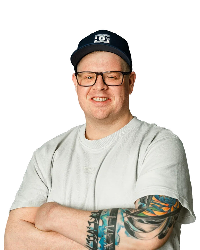 Lutz Bölling, lächelnd mit Cap und Brille, die Arme verschränkt